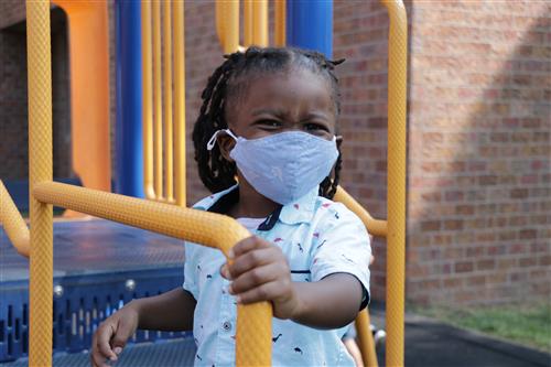 A child stands on playground equipment